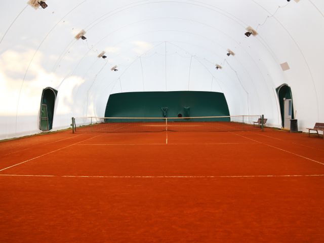 Struttura sportiva con campi da tennis in terra rossa.